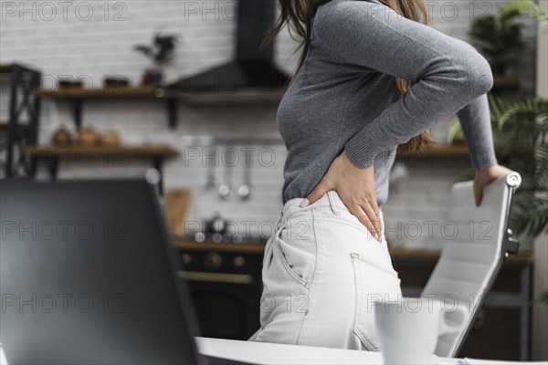 Side view woman having backache while working from home