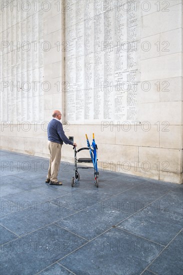 A senior citizen with a walker stands in the Men's Gate