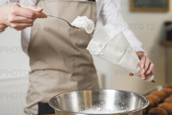 Female baker filling whipped cream white icing bag