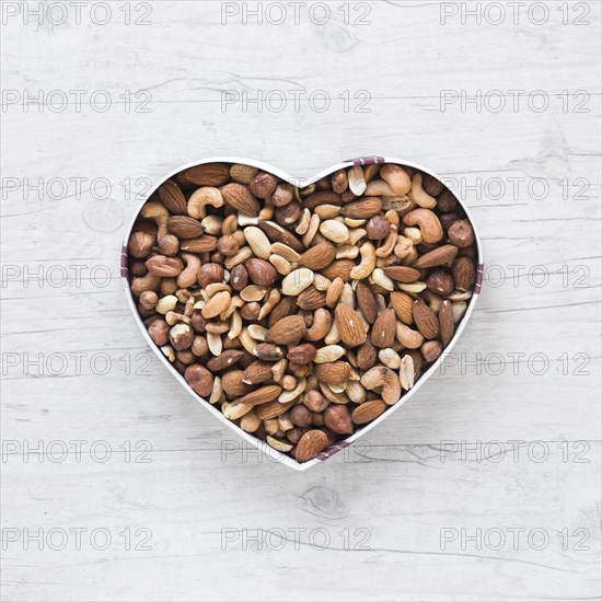 Top view healthy dryfruits heart shape wooden desk