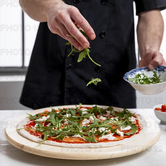 Man putting arugula pizza dough