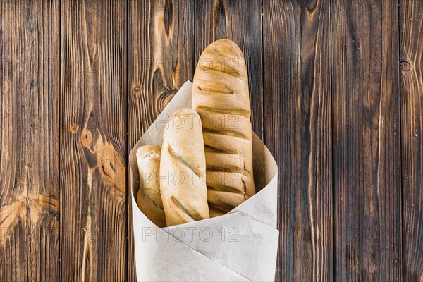 Baguettes wrapped paper wooden background