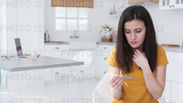 Worried woman holding pregnancy test