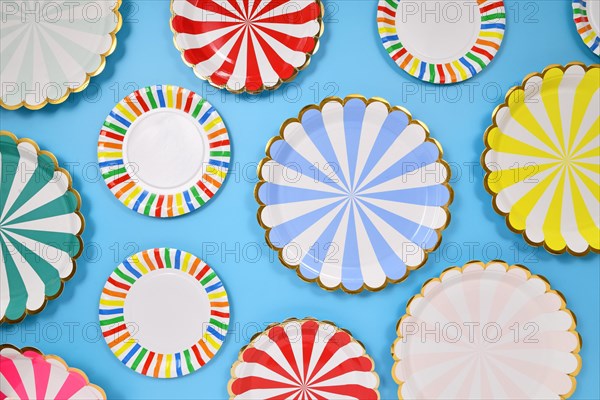 Different colorful striped paper party plates on blue background