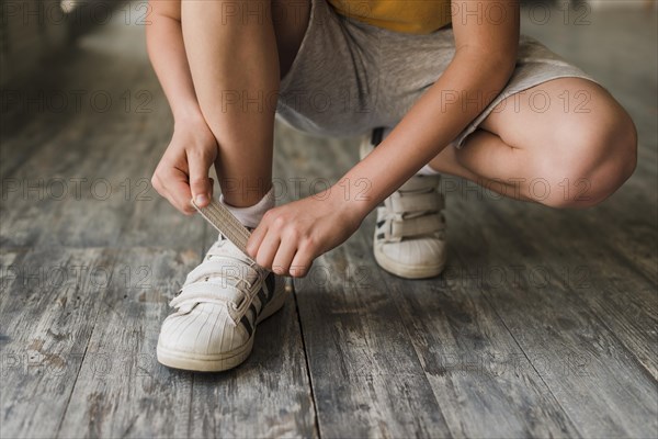 Low section boy putting shoe strap hardwood floor