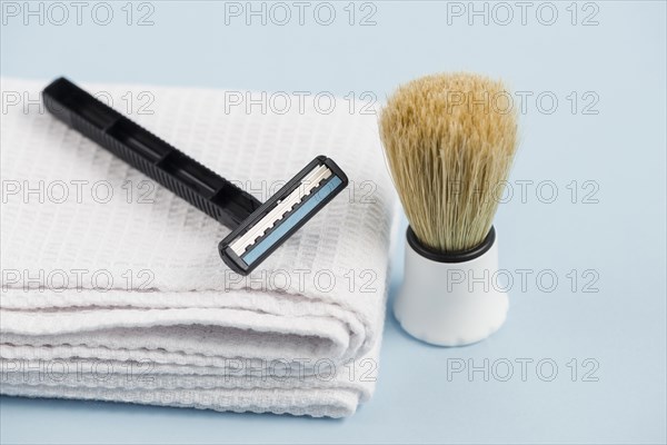 Razor white folded napkin classic shaving brush against blue background