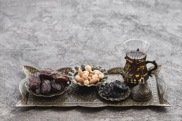 Traditional turkish arabic tea glasses dates nuts metallic tray concrete backdrop