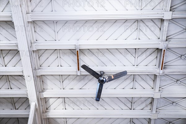 Fan in front of a white wooden ceiling