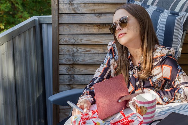 Beautiful young caucasian woman is dreaming about something while writing a greeting card