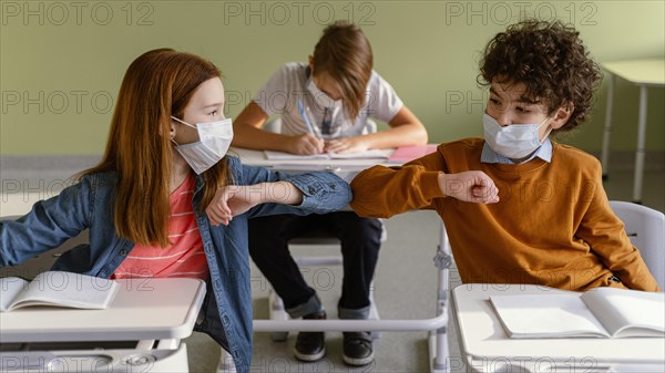 Front view children with medical masks doing elbow salute class