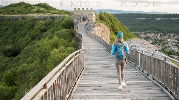 Back view traveller walking down bridge