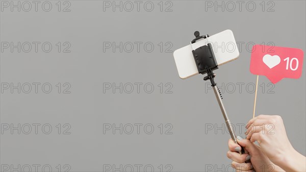 Close up blogger holding selfie stick with mobile phone