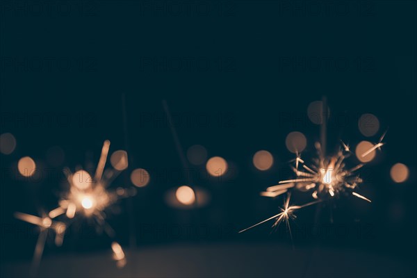 Sparklers burning dark bokeh background