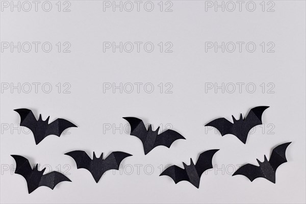 Black papercraft flying Halloween bats at bottom of gray background with empty copy space