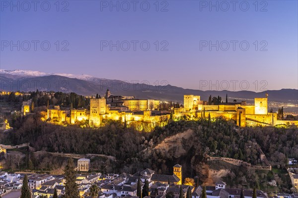 View from the Mirador de San Nicolas of Alhambra and the snow-capped mountains of the Sierra Nevada at dusk