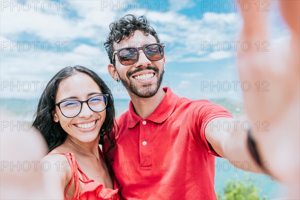 Happy Young couple on vacation taking a selfie near the beach. Smiling young couple taking a self portrait in the bay of San Juan del Sur