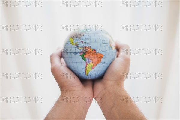 Person s hand holding small globe
