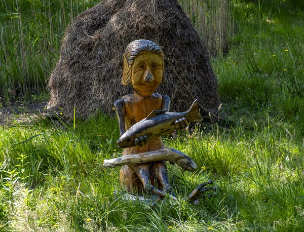 Wooden figure with fish in hands on the bank of the Spree