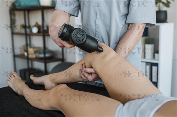 Male physiotherapist using equipment female patient during physical therapy session