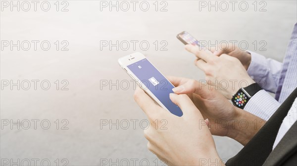 Woman using facebook application mobile near man wearing smart watch