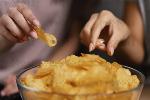 Women couch watching tv eating chips close up