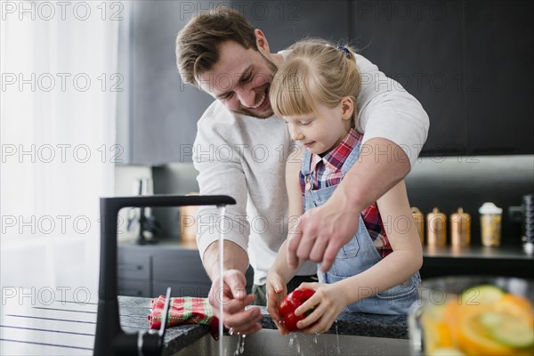 Girl helping father wash vegetables