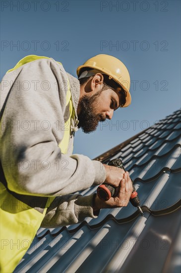 Man working roof with drill low view