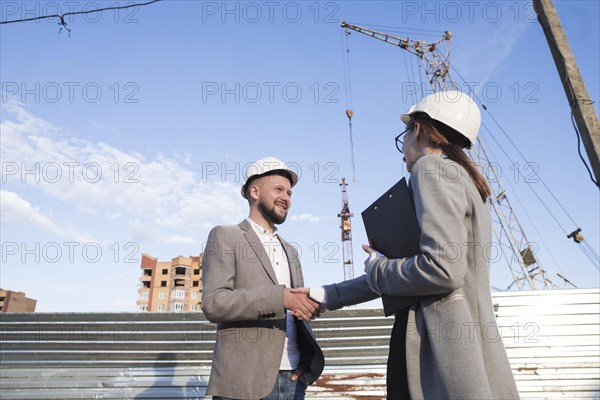 Smiling engineers shaking hands construction site architectural project