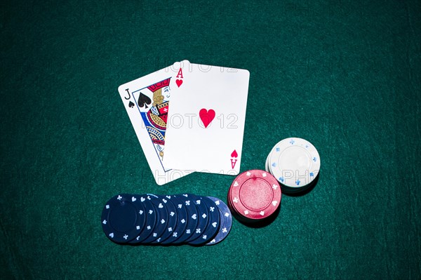 Jack spade heart ace card with casino chips stack green poker table