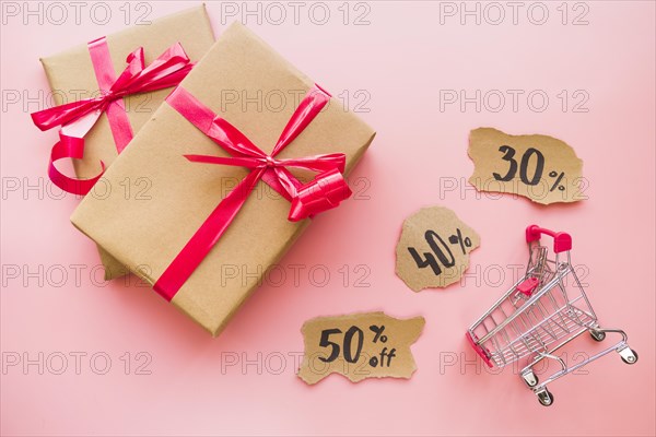 Gift boxes with red bows near shopping trolley