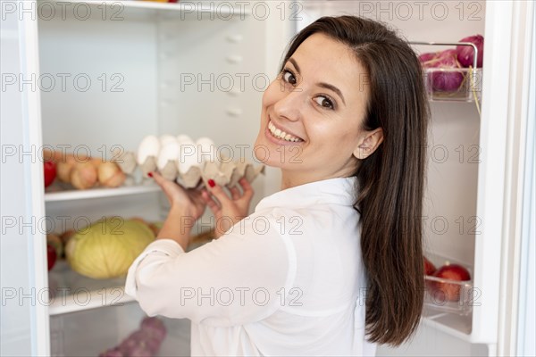 Medium shot smiley girl holding carton eggs