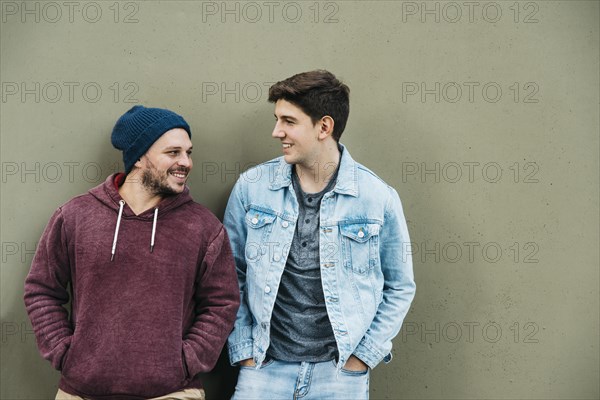 Young friends standing near grey wall