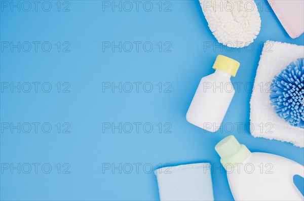 Different type sponges with detergent bottles blue backdrop