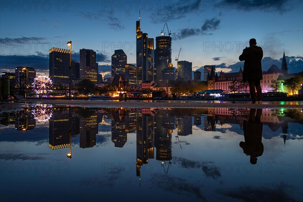 The colourful lights of the Mainfest are reflected in a puddle. The Mainfest on the Mainkai