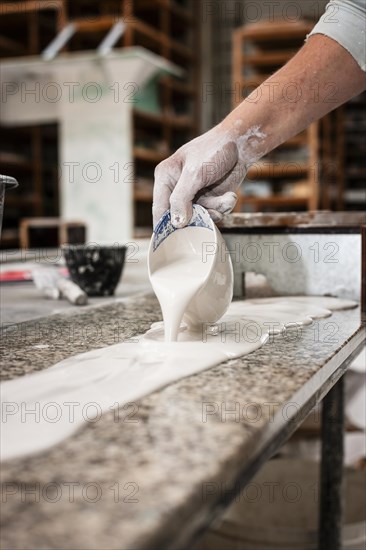 A plasterer pours plaster onto a workbench