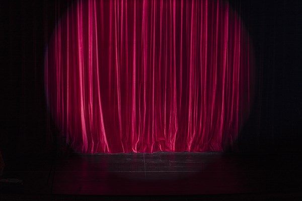 Empty stage with light spot on red curtain