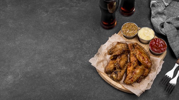 High angle fried chicken wings with variety sauces fizzy drinks