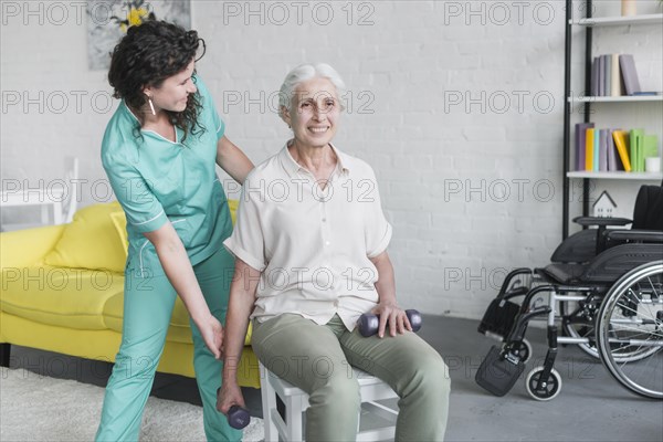 Young pretty nurse assisting old woman his therapy