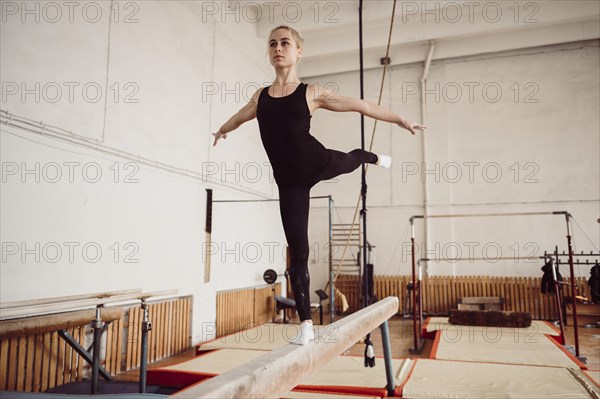 Front view blonde woman training balance beam