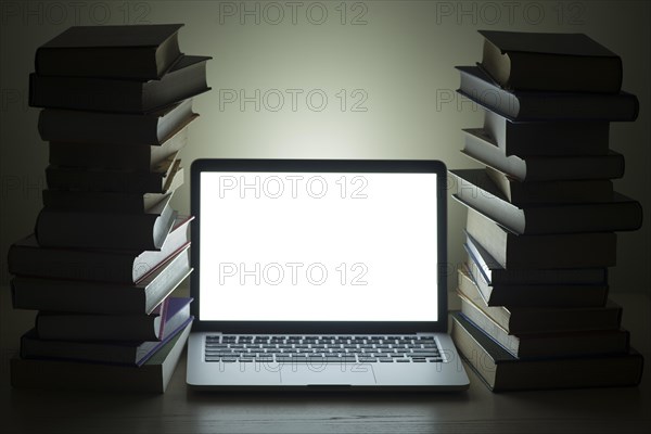 Laptop dark stacked books