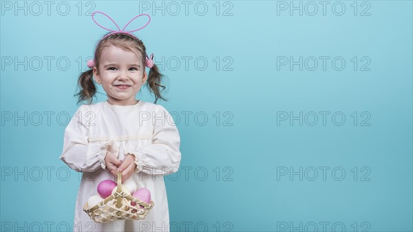 Little girl bunny ears holding basket with easter eggs