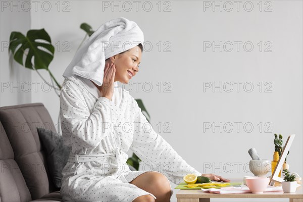 Side view woman bathrobe using skincare