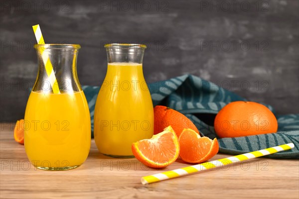 Lemonade made from citrus fruits in small bottle jars with drinking straws and fruit slices on wooden table