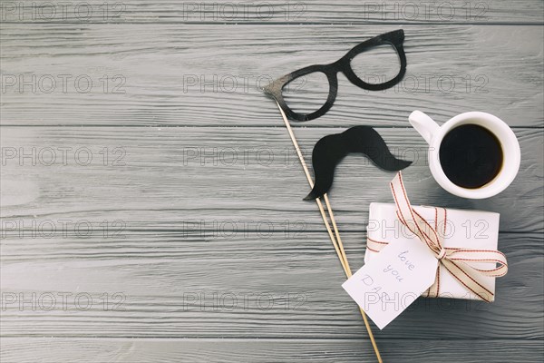 Decorative eyeglasses moustache near present mug beverage