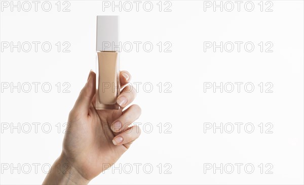 Hand holding foundation bottle with copy space