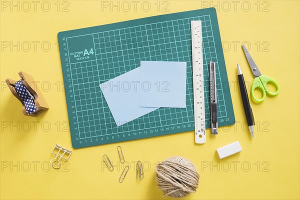 Elevated view green cutting mat stationeries yellow background