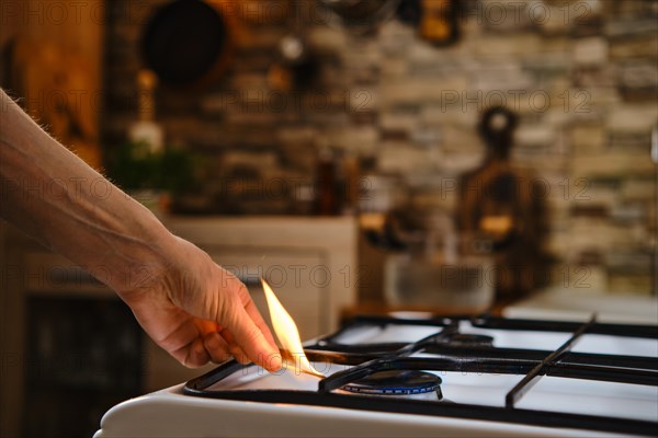 Unrecognizable man lights gas on the stove with match