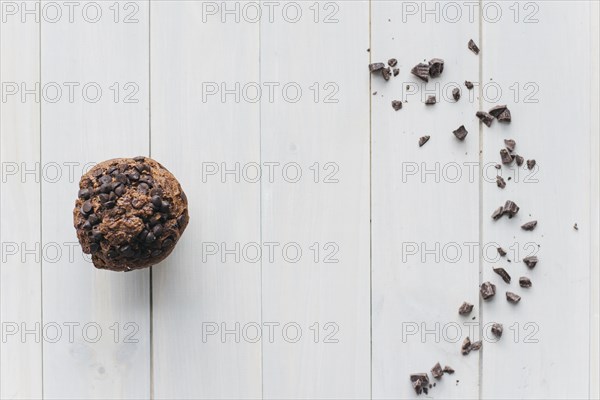 Elevated view choco chip cupcake scattered chocolate wooden background