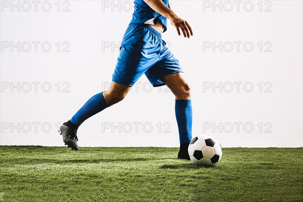 Crop football player shooting ball