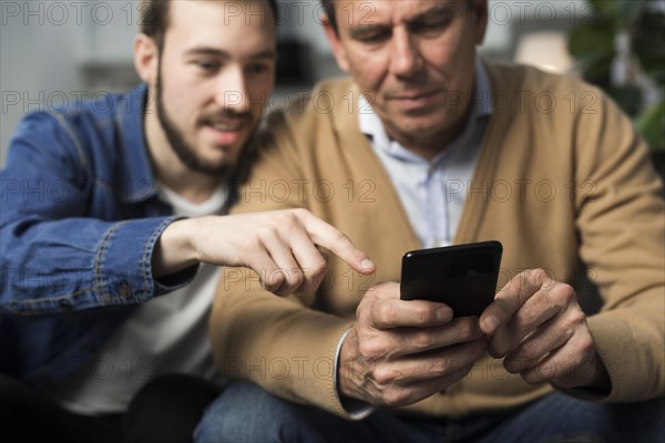 Father son looking phone living room